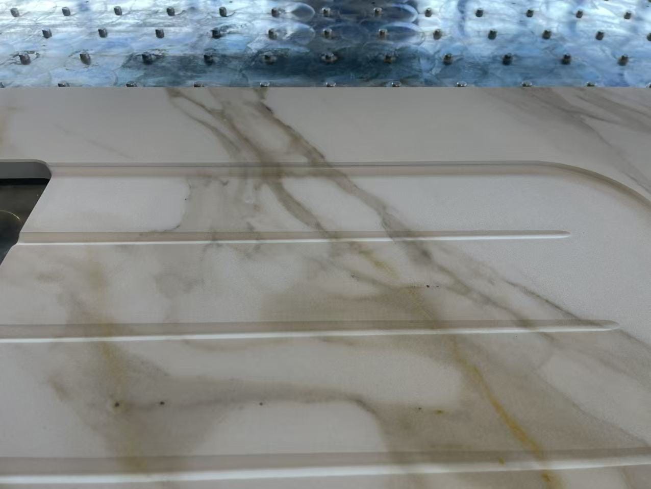 A pale vein design across a worked mineral top with integrated grooves.